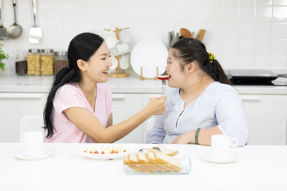 Support worker helping to feed disabled woman