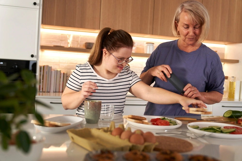 Disabled woman cooking with support worker in kitchen